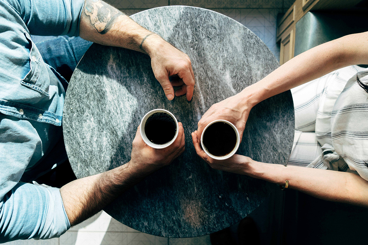 Two people holding coffee cups at a table