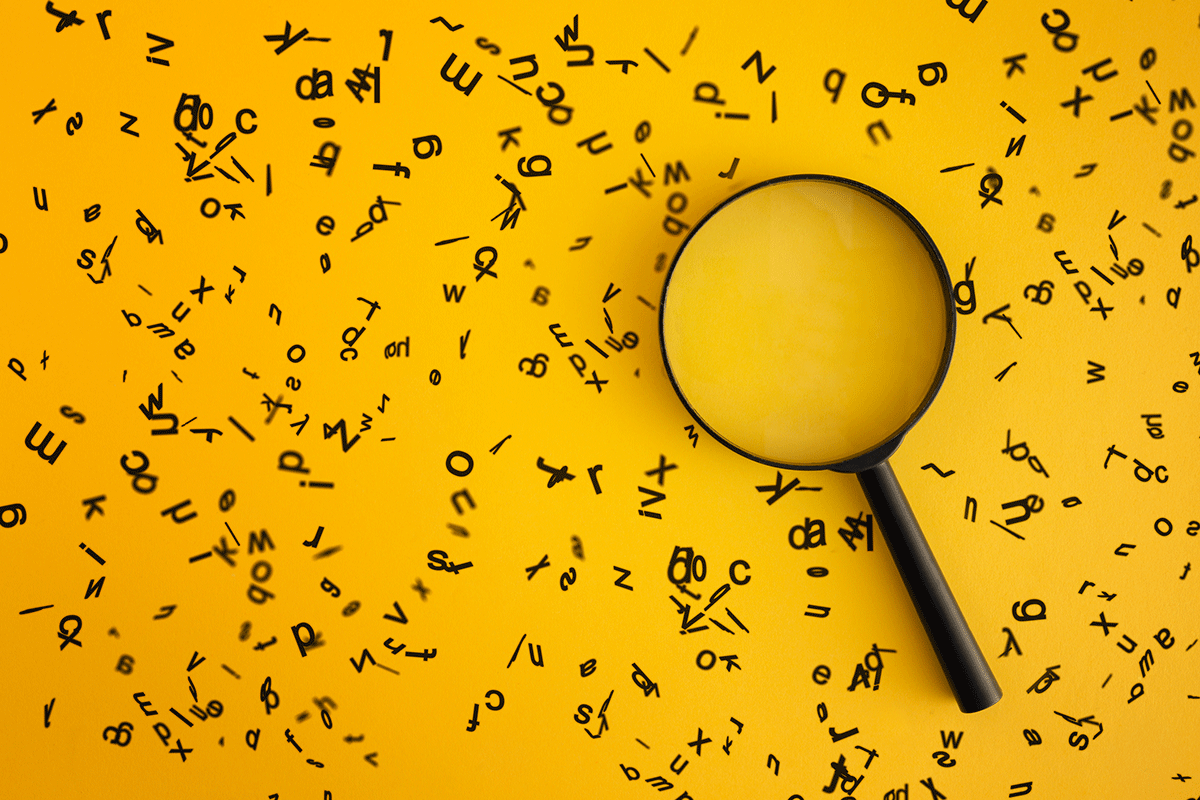 Black letters are spread across a yellow background. A magnifying glass sits on top of the letters.