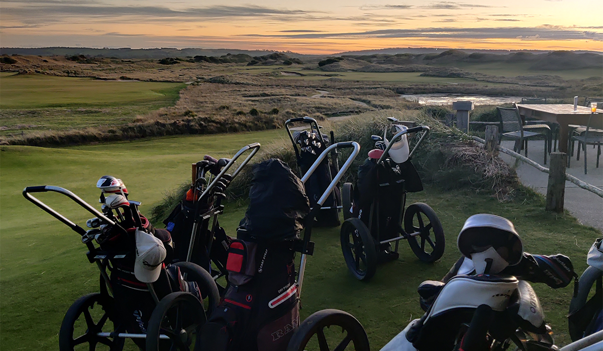 Golf carts on a hill overlooking Tasmania's Barnbougle golf course at sunrise.