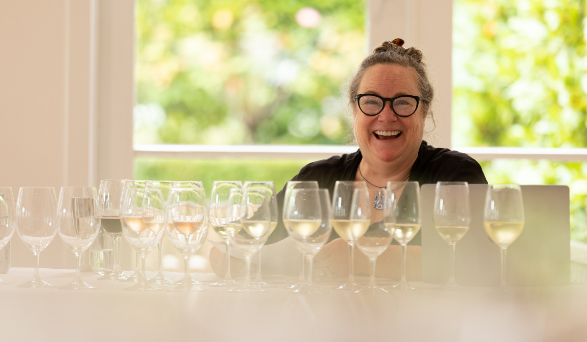 A woman smiling while tasting wine