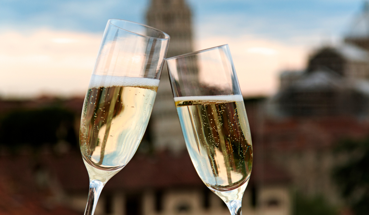 Two glasses of sparkling toasting with an Italian scene in the background