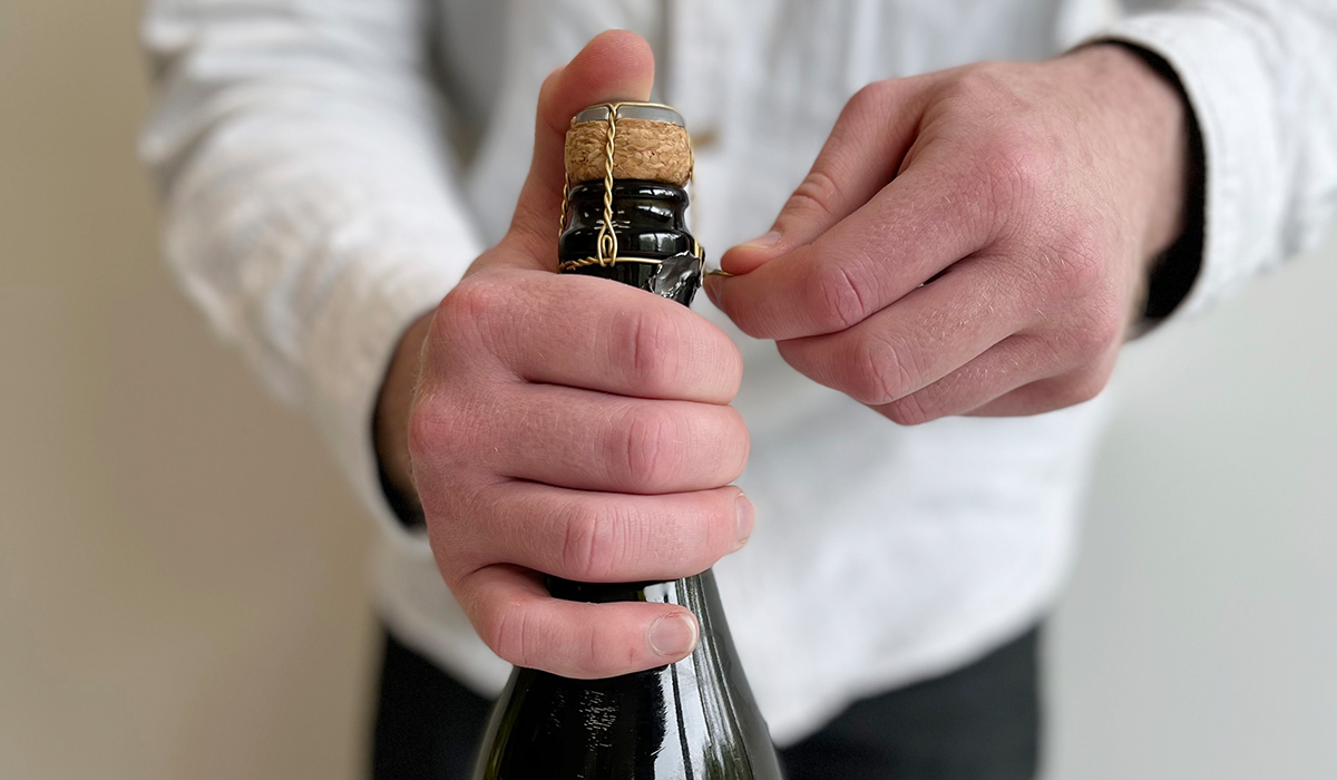 The cage being removed from a bottle of sparkling wine