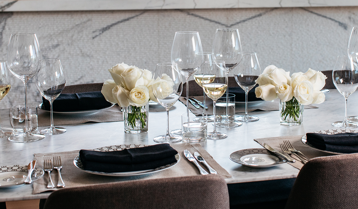 A table set with RIEDEL glassware and white roses.