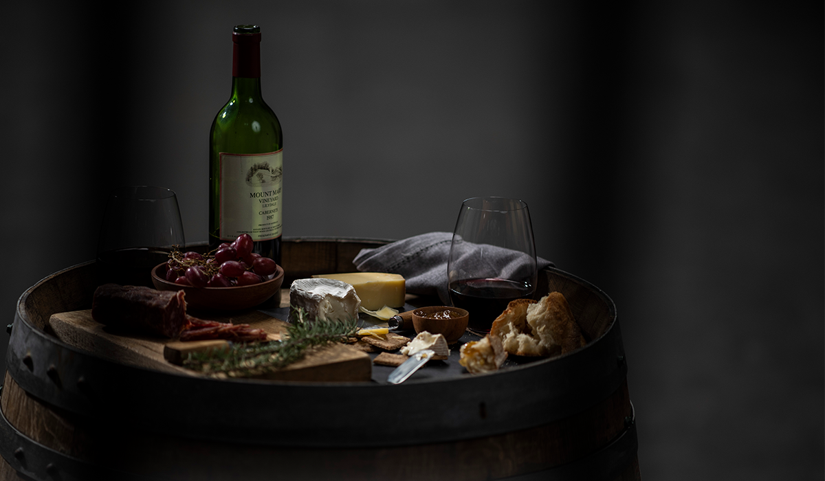 A bottle of Mount Mary and a cheese spread on a wine barrel