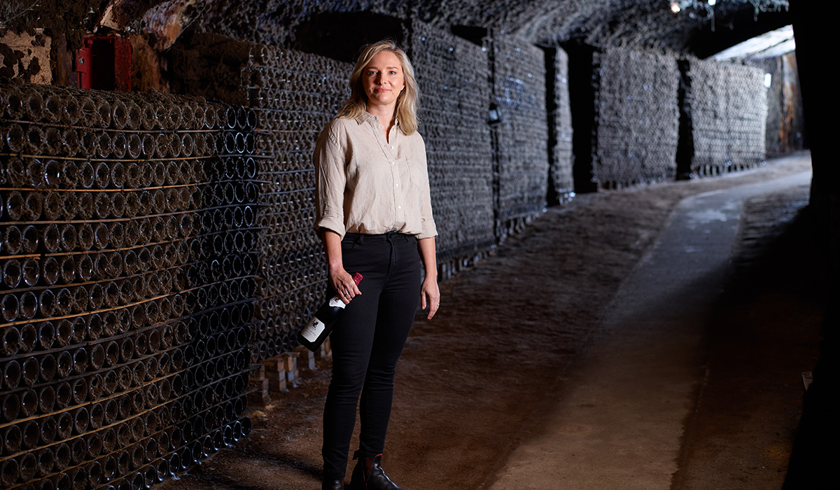 Winemaker Clare Dry in the Seppelt cellar holding a bottle of wine.