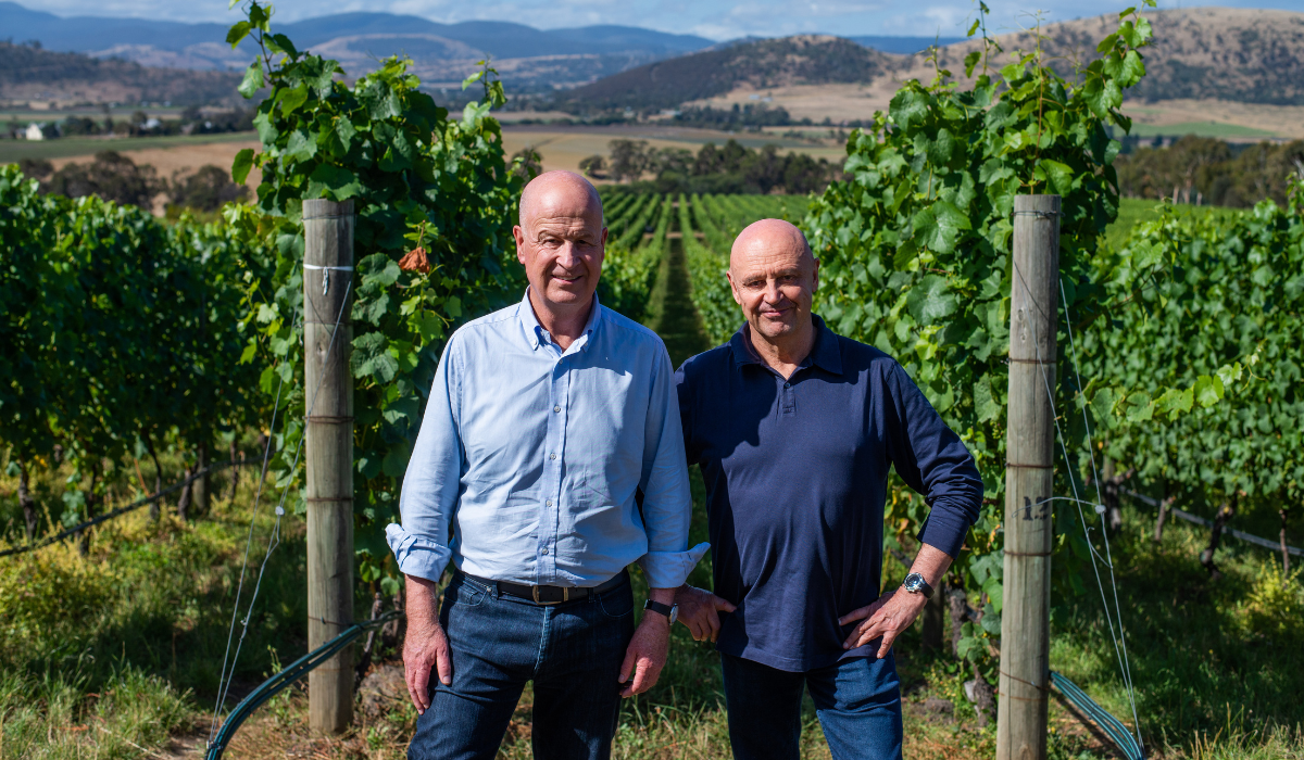 Two men standing in front of a vineyard