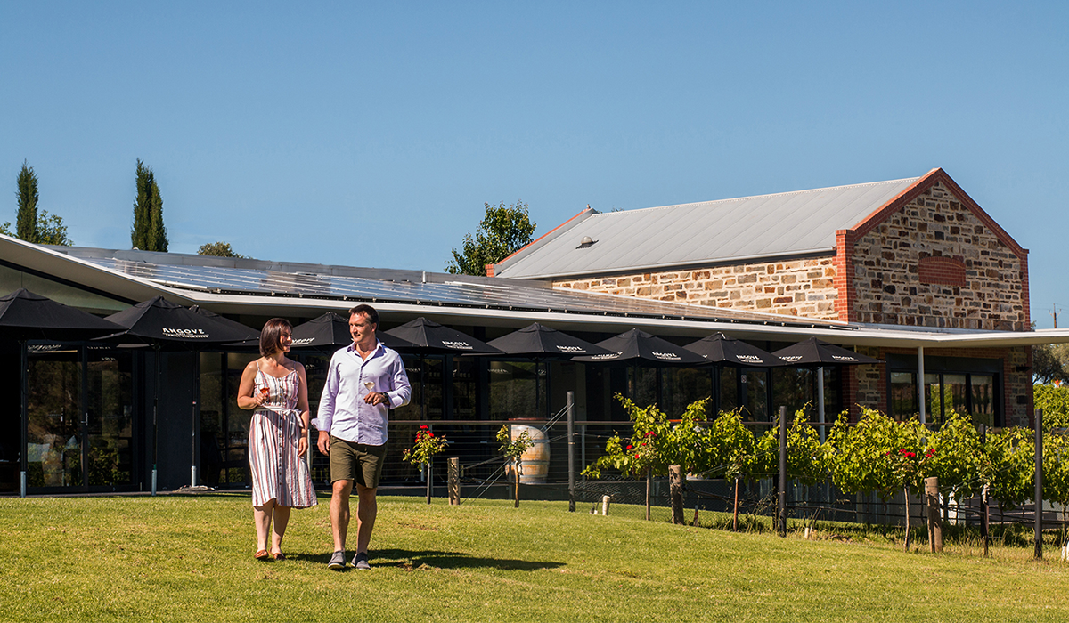 A man and a woman walk on lawn outside winery
