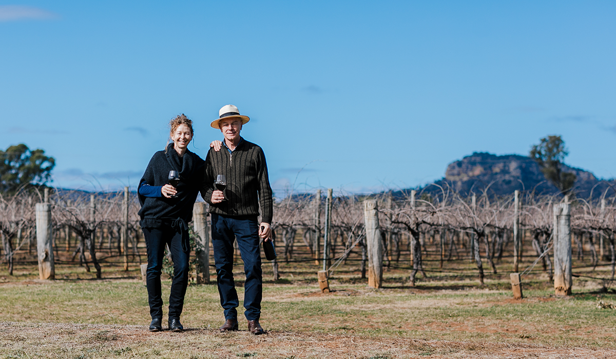 Man and woman standing in front of vineyard