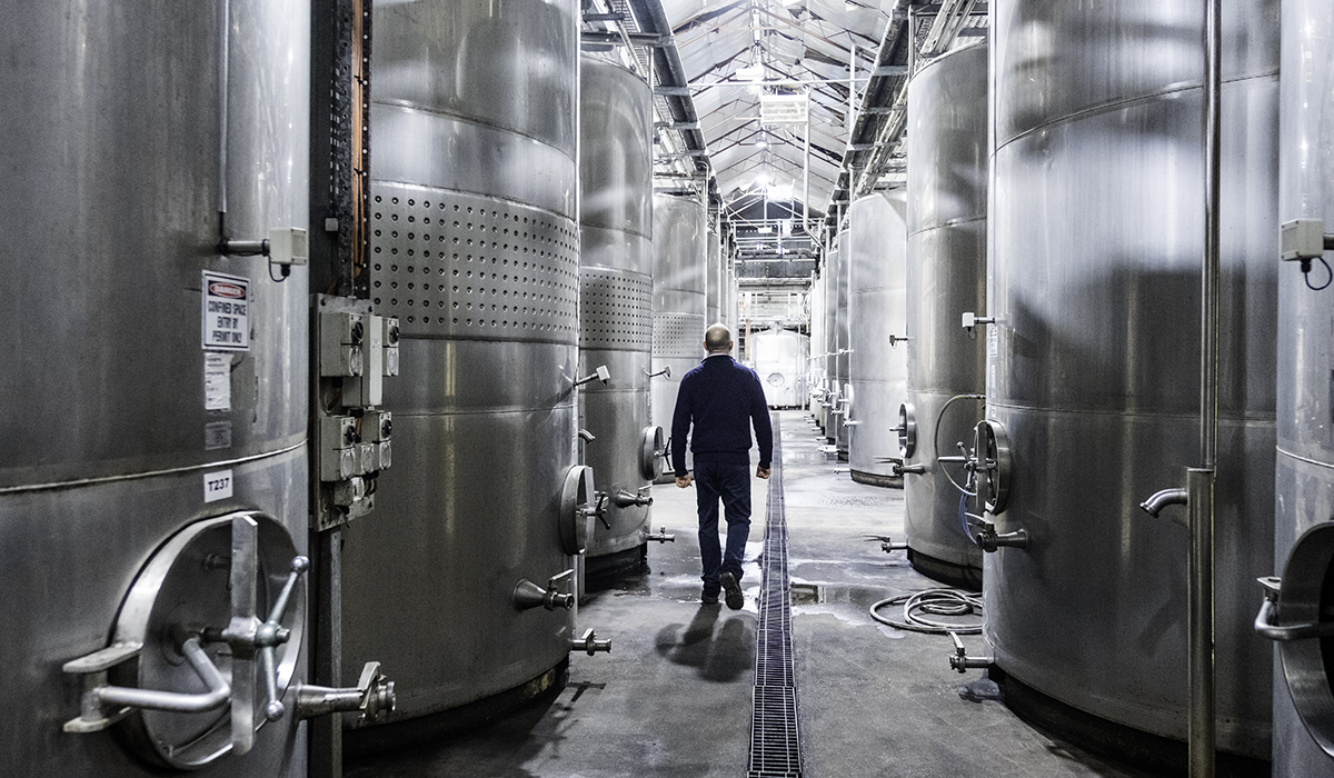 Man walking between steel wine vats