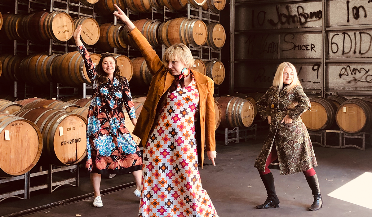 Women strike a pose in front of wine barrels