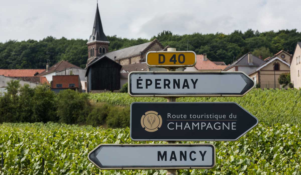 Sign of the tourist route in Champagne with vineyards and a village in the background.