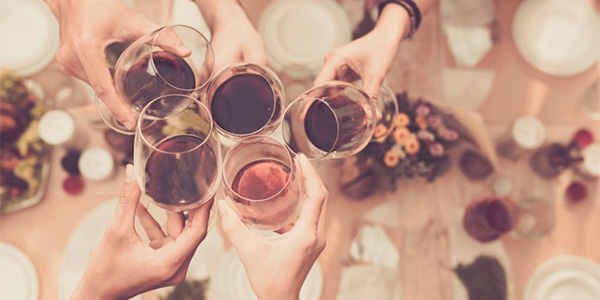 Friends clinking red wine glasses over table