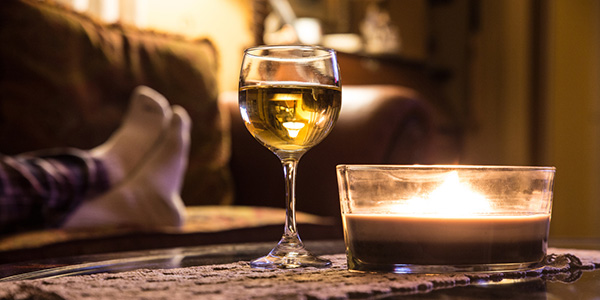 Glass of wine on coffee table with person on couch in the background