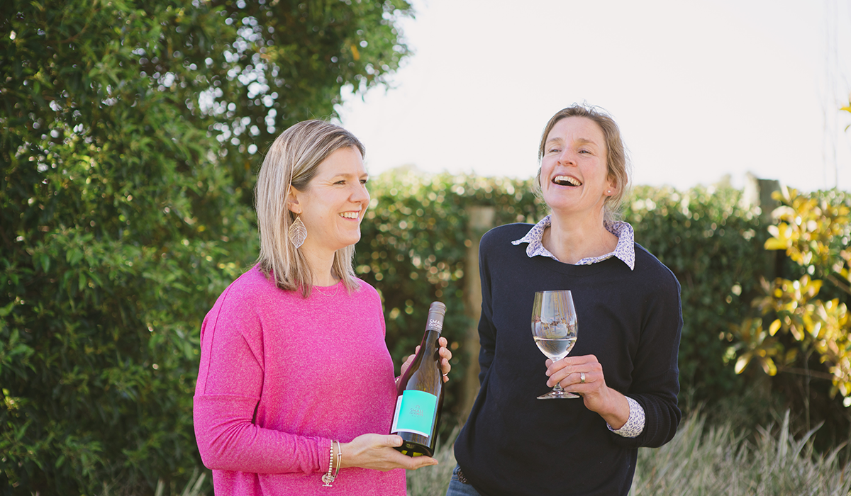 Bec and Jules from Small Victories in the vineyard holding wine