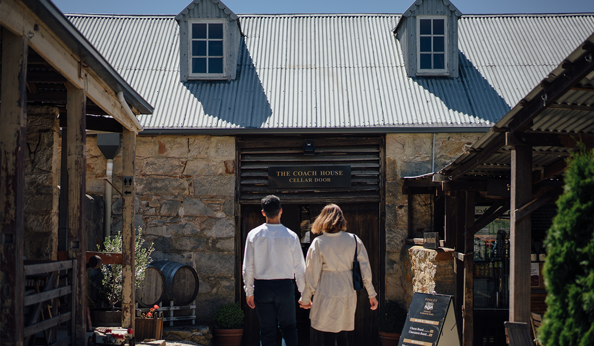 Two people holding hands walking into the Pooley cellar door.