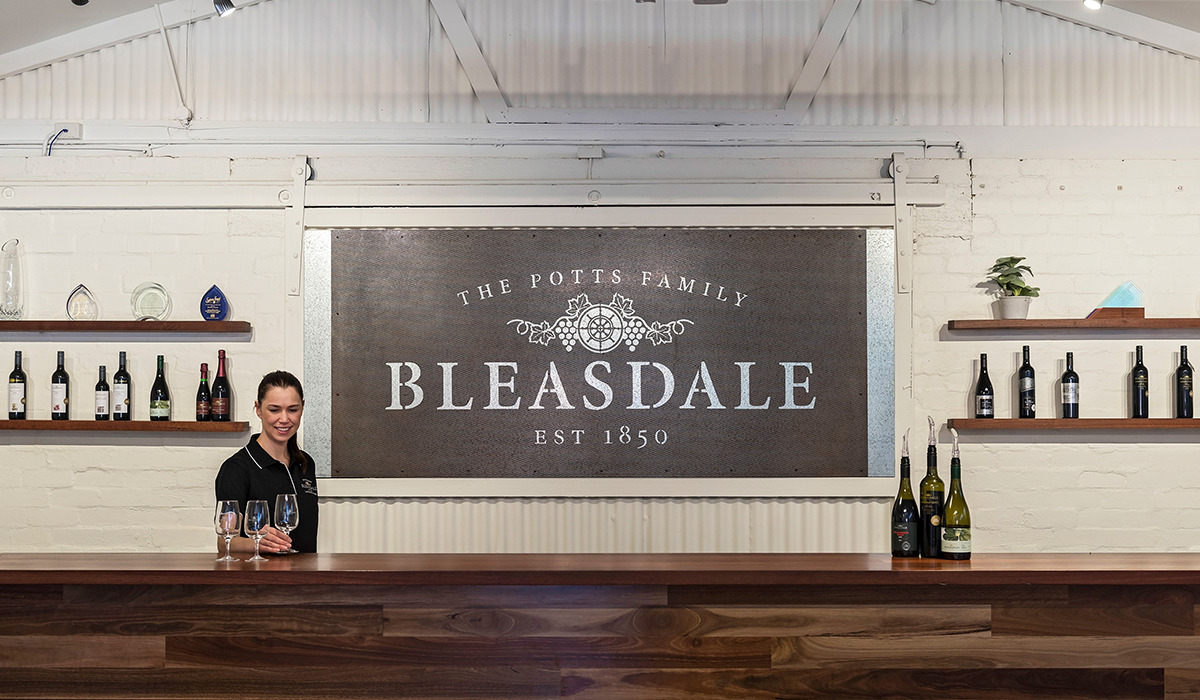 A team member behind the counter at the Bleasdale cellar door with the Bleasdale sign on the wall