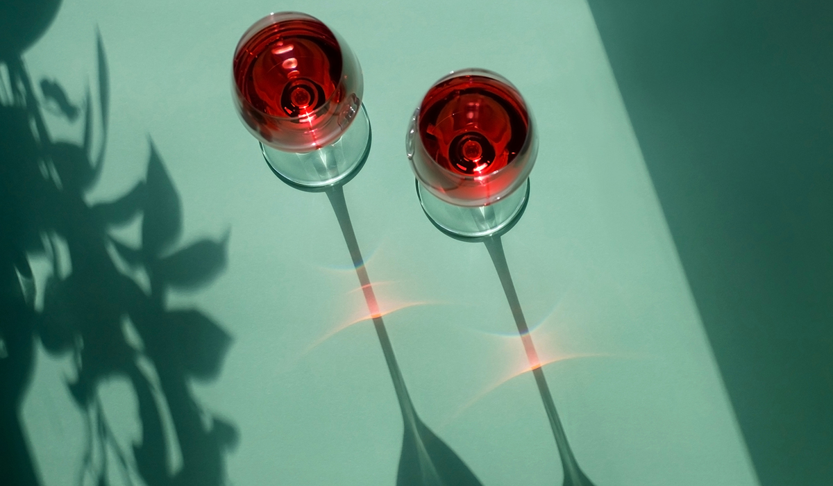 Two glasses of red wine on a light green background.