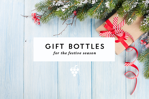 Gift bottles - blue wooden background with present and pine leaves